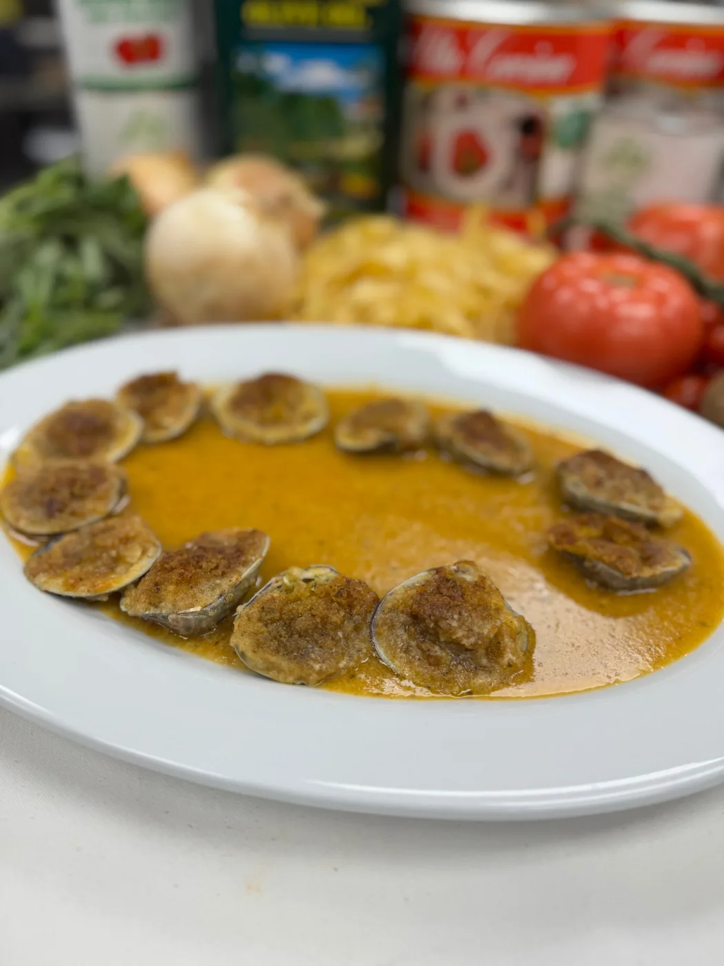 A ring of baked clams stuffed with garlic parmigiana breadcrumbs on a white plate