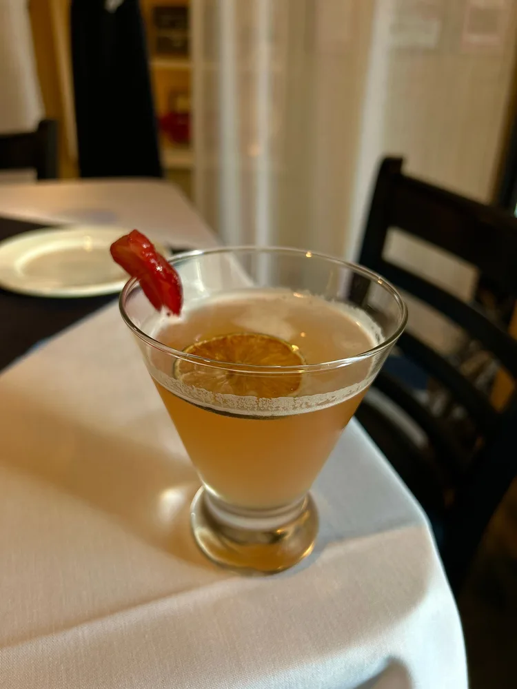 Capri martini garnished with a red chili on a white tablecloth